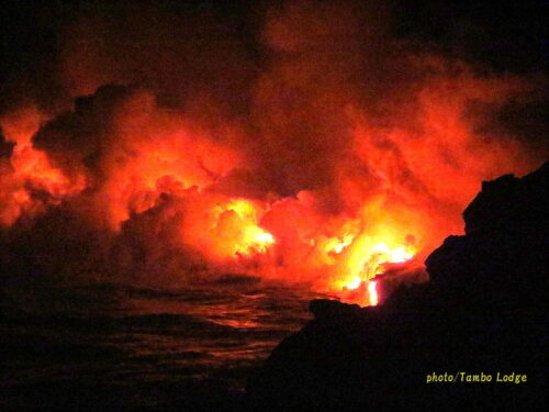 燃える火山の溶岩流が海へと流れ落ちる
